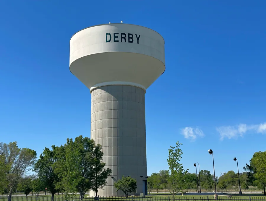 Derby water tower with the city name above trees and an athletic field